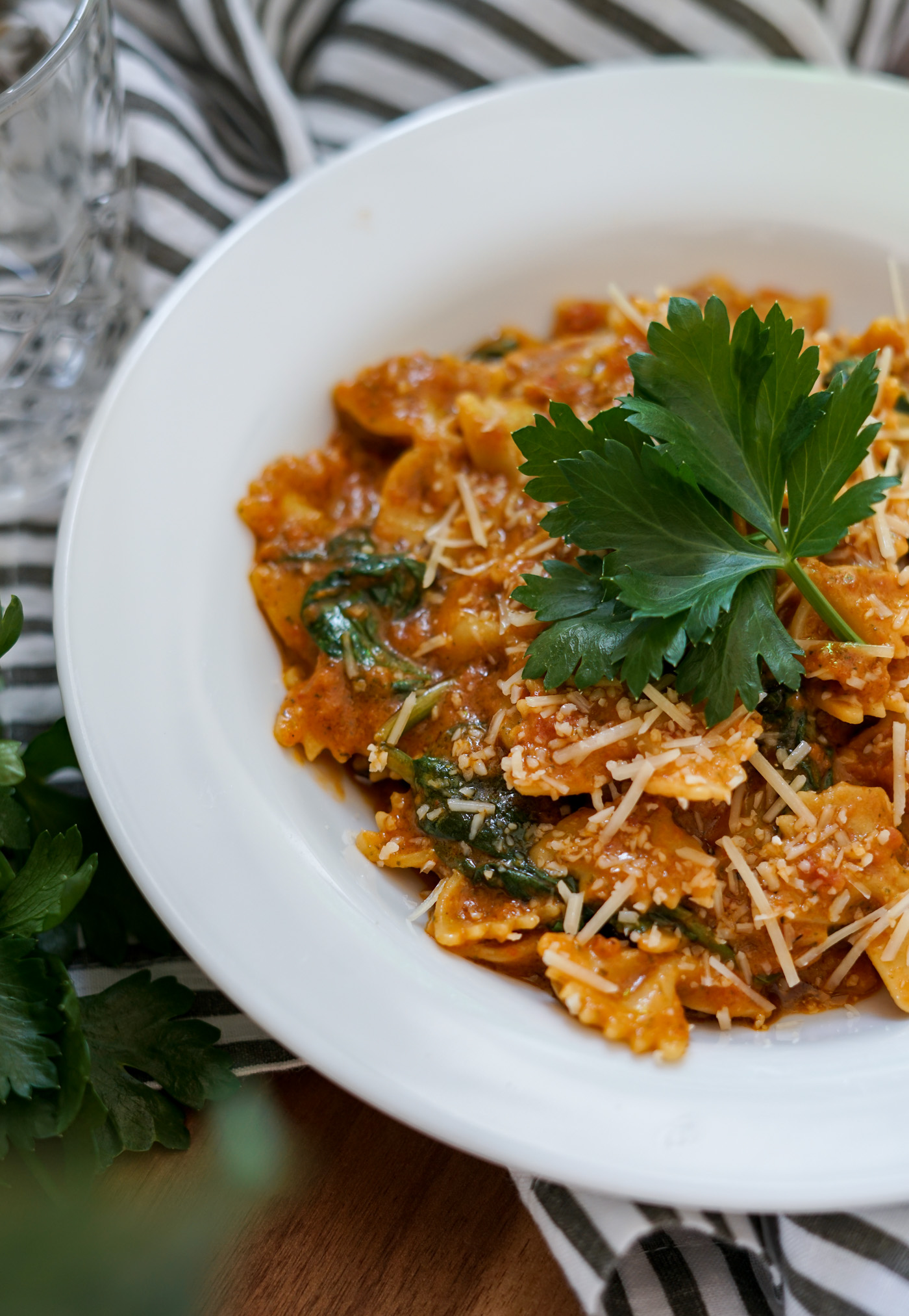 Large bowl of vegan sun dried tomato pasta topped with fresh parsley